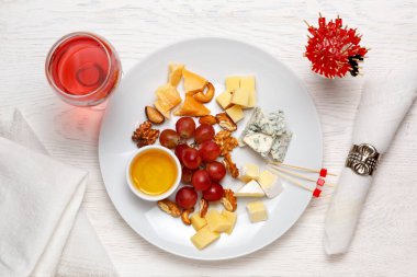 Üzüm, fındık ve bir bardak gül şarabı ile servis edilen peynir tabağı. Çeşit çeşit peynirli Camembert peyniri, Brie peyniri, Parmesan peyniri, keçi. Üst görünüm