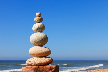 Dengeli taşların Zen piramidi yaz denizi ve mavi gökyüzünün arka planında. Manevi uyum, denge ve meditasyon kavramı