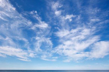 Sirrus ve küçük kümülüs bulutlarıyla deniz üzerinde güzel bir gökyüzü. Arkaplan resmi. Ufkun çizgisi