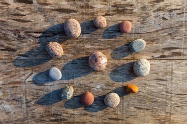Gri eski ahşap bir yüzey üzerinde çok renkli çakıl taşlarının dairesel deseni. Spa dekorasyonu. Meditasyon ve rahatlama konsepti. Düz yatış, üst görünüm
