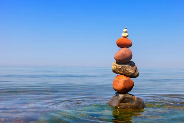 海の背景に水の中に立ってカラフルな小石のロック禅ピラミッド バランス 瞑想の概念 — ストック写真