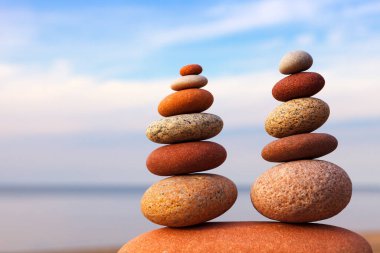 İki Rock zen piramidi, denizin arka planındaki kumsalda renkli çakıl taşları. Yaşam dengesi, uyum ve meditasyon kavramı