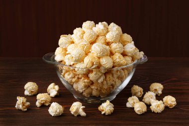 Taze, tatlı patlamış mısır ve karamel. Koyu ahşap bir masanın arka planında altın rengi..