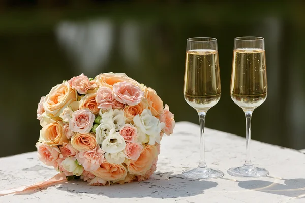 Van de bruid boeket en twee glazen van champagne — Stockfoto