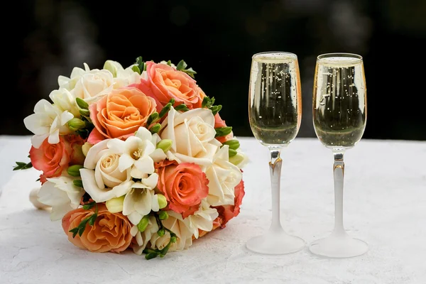 Два бокала игристого вина и букет невесты — стоковое фото