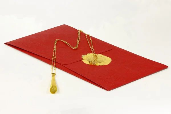 Золотое ожерелье и красный конверт — стоковое фото