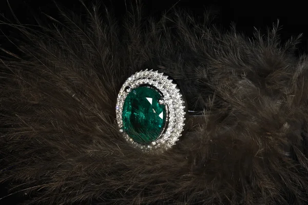 Σμαράγδι δαχτυλίδι με διαμάντια σε φόντο φτερά — Φωτογραφία Αρχείου