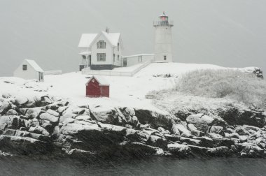 Maine's Nubble Lighthouse Shines During Snowstorm. clipart