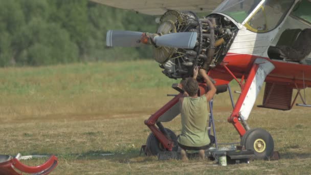 Инженер ремонтирует двигатель самолета на поляне — стоковое видео