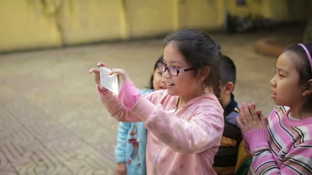 Hanoi, Vietnam - 12 mars 2015: asiatiska barn försöka ta foto med smartphone — Stockvideo