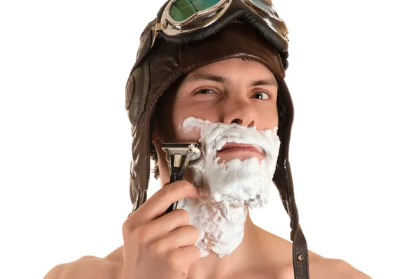 man shaving in flight helmet and flying goggles
