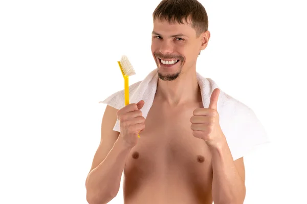 Smiling adult naked man with big bright yellow toothbrush in his right hand raised and the thumb on left hand with white towel Royalty Free Stock Photos