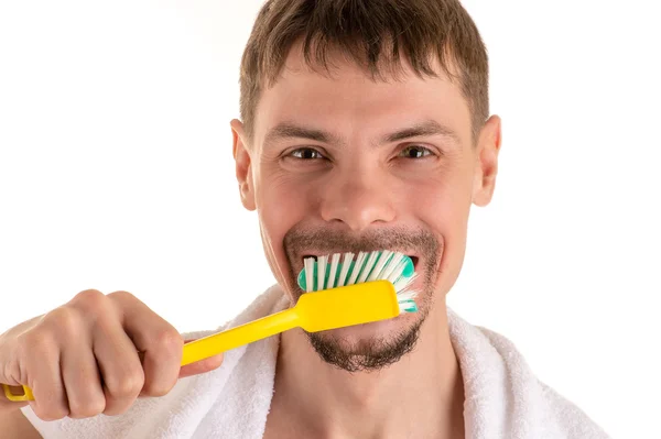 Erwachsener lächelnder Mann mit großer gelber Zahnbürste in der Hand und weißem Handtuch Stockfoto