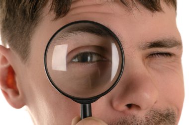 young man looking through a magnifying glass closeup clipart