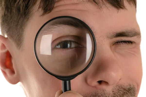 young man looking through a magnifying glass closeup