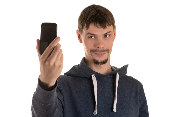 Молодой человек улыбается фотографиям себя на телефон — стоковое фото
