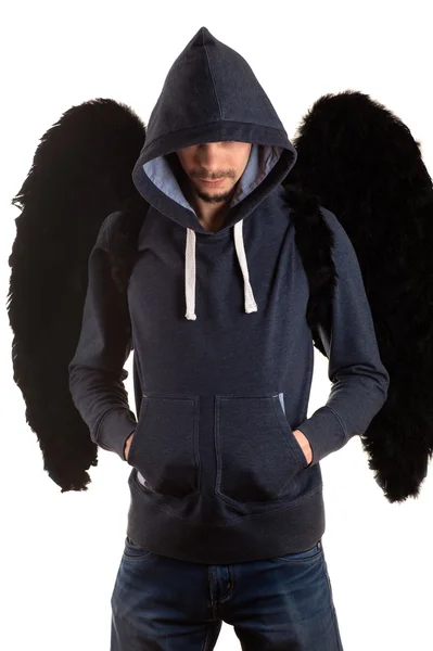 Mann steht mit den Händen in den Taschen und auf dem Rücken mit schwarzen Flügeln Stockfoto