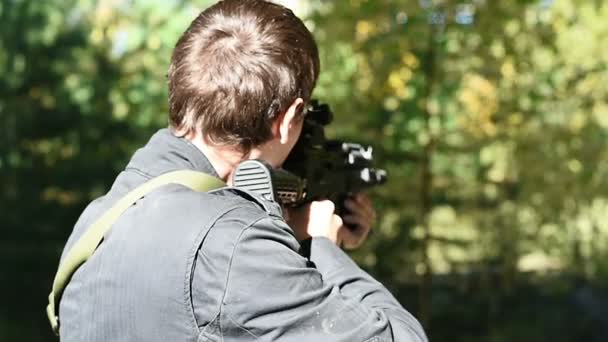 Homem com a arma visa a visão traseira, em seguida, lateralmente — Vídeo de Stock