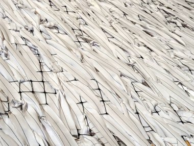 Parlak beyaz mermer kumaşın dokusu dalgalı ve dalgalı, beyaz kırışıklıklar soğuk şeritleri katlar.