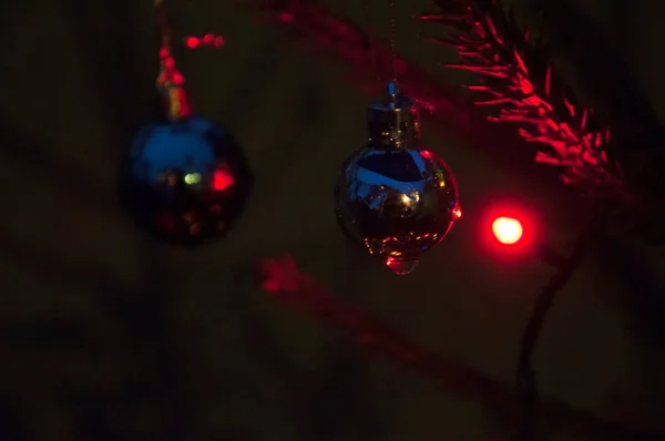 Kerstversiering 's nachts op een kerstboom in het licht van bloemenslingers — Stockfoto