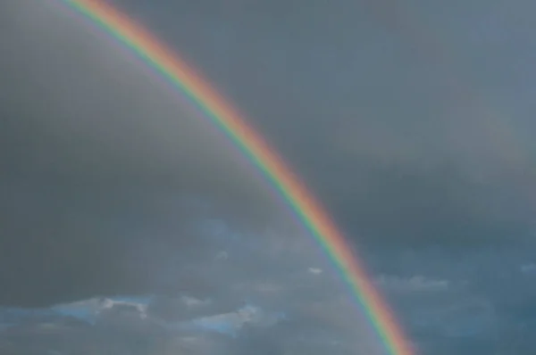 Rainbow arc on cloudy sky