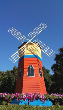 Bahçede açık mavi gökyüzü ile bir renkli Hollanda tarzı yel değirmeni 