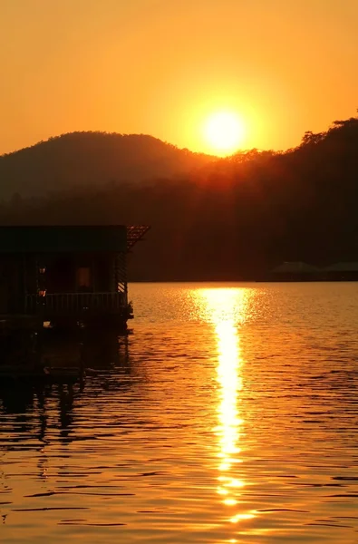 Silhouette of wooden floating house during golden sunset — Stock Photo, Image