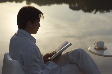 adam sabah göl yanında kitap okuma