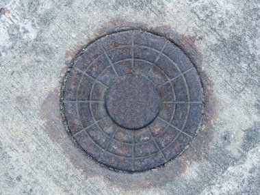 Old rusty iron manhole cover on concrete floor