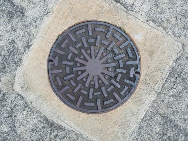 Rusty iron manhole cover on concrete floor