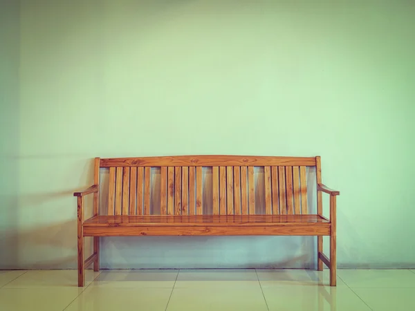 Single wooden bench against the concrete wall (vintage style tone)