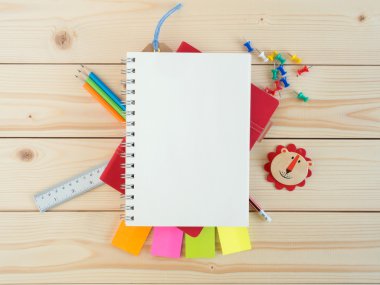 Kopya alanı için tahta masaya boş kitap ve renkli kırtasiye malzemesi