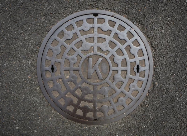 Circle steel manhole cover on asphalt street in Japan