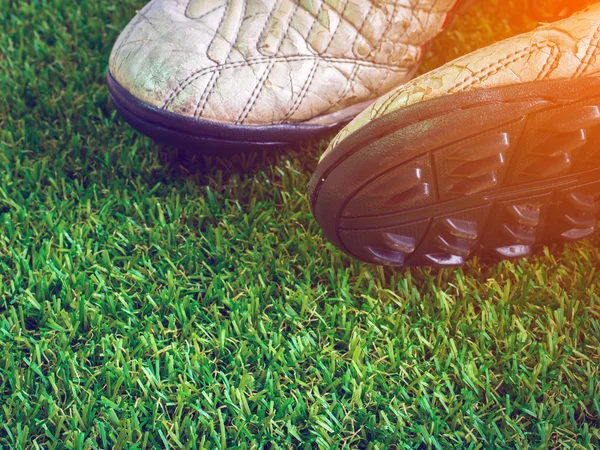 Kopya alanı ile suni çim üzerinde eski çamurlu kirli futbol ayakkabıları