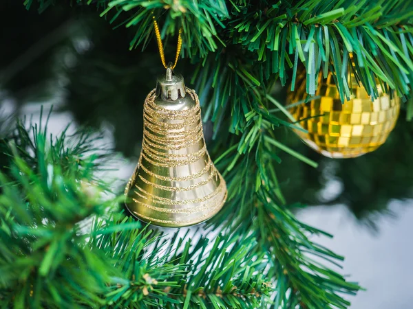 Zvonek zlatý prsten zavěšení na vánoční stromeček s rozostření pozadí, — Stock fotografie