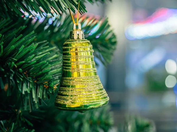 Χρυσή πράσινο δακτύλιο καμπάνα κρέμεται από το χριστουγεννιάτικο δέντρο με backg θαμπάδα — Φωτογραφία Αρχείου