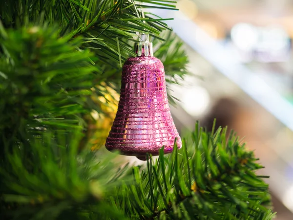 Pink ring bell hanging on Christmas tree with blur background, s