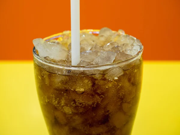 Feche uma xícara de refrigerante na mesa amarela com laranja — Fotografia de Stock