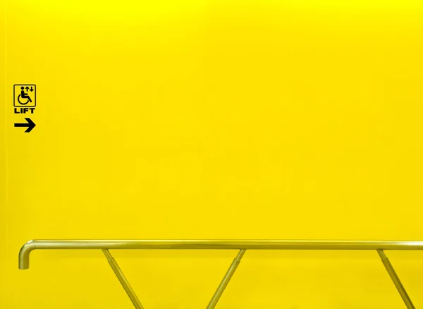 Σηκώστε το σημάδι για άτομα με ειδικές ανάγκες σε κίτρινο τοίχο με κουπαστή — Φωτογραφία Αρχείου