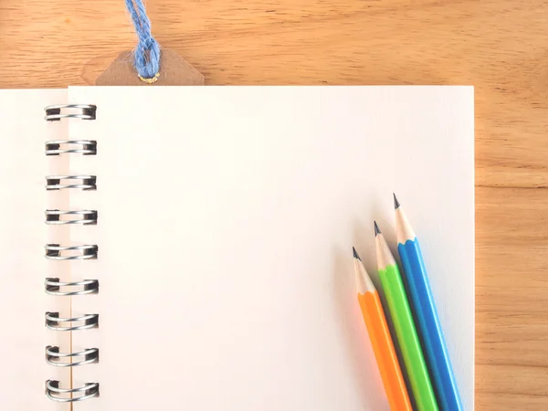 Lápis coloridos e papel de livro em branco na mesa de madeira — Fotografia de Stock