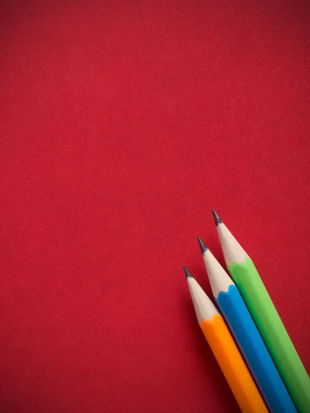 Kırmızı deri kitap kapagina renkli kalemler — Stok fotoğraf