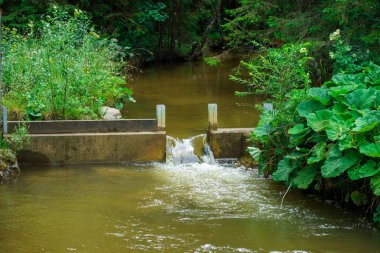 A small concrete dam on a mountain river in the Austrian Alps from flooding after the melting snow