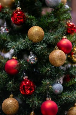 Kırmızı, gümüş ve altın toplarla süslenmiş yapay Noel ağacı dalları.