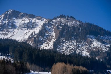 Avusturya Alpleri 'ndeki dağ zirveleri öğlen güneşinde hafifçe karla kaplı.