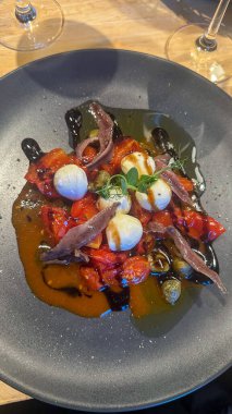 Ançüezli taze aperatif, mozzarella peyniri, kiraz domatesleri, kapari, zeytinyağı ve balzamik sirke ve bir tutam otla süslenmiş.