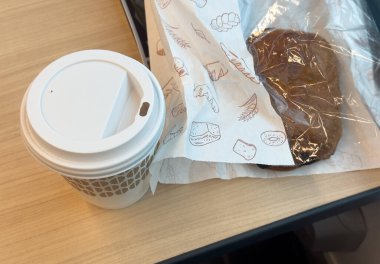 Kese kağıdında tatlı hamur işleri ve tren kompartımanındaki masaya koymak için bir bardak kahve. Kahvaltınız hazır. Paket servis.