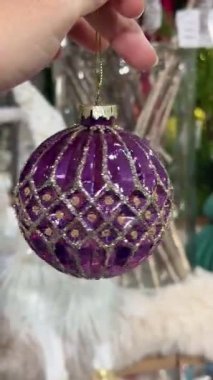 Zarif mor Noel süsü, altın parıltılı detaylar elle tutulur, gösterişli bayram dekorasyonu stili.