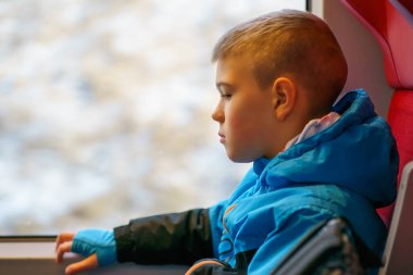 Küçük çocuk trenin penceresinde oturup dışarıdaki manzarayı seyrediyor. Merakını, sakinliğini, çocukluk yolculuğunu ve sessiz yansımasını ifade ediyor..