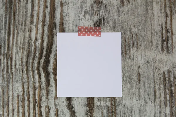 Nota branca com fita, em um fundo de madeira — Fotografia de Stock