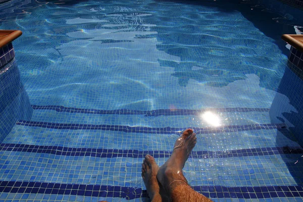 Pies humanos en una piscina, agua transparente — Foto de Stock